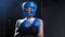 Tattooed woman in protective soft helmet puts on boxer gloves and stands in the fight pose