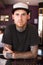 Tattoos, creative and portrait of a man with tattoos standing by the counter of his artistic studio. Confident, cool and
