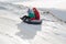 TAU SAMALY, KAZAKHSTAN - DECEMBER 23, 2023: happy Kazakhs family tubing down a slide in winter with snow at Tau Samaly