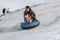 TAU SAMALY, KAZAKHSTAN - DECEMBER 23, 2023: happy Kazakhs family tubing down a slide in winter with snow at Tau Samaly