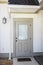 A taupe rear side back door of a new construction cream color house with hardy board siding near the patio entrance