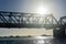 Tauranga railway bridge crosses harbour back-lit by bright sun in silhouette