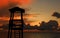 Tawny cloudy sunset silhouetting life guard post watch tower