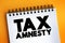 Tax Amnesty - opportunity for people who owe back taxes to pay some or all of what they owe, text concept on notepad