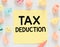 TAX Deduction words written on a small yellow piece of paper