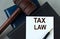 TAX LAW - words on a white sheet with leather notebooks, a judge\\\'s hammer and a pen