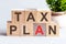 TAX PLAN word written on wood block. Faqs text on table, concept