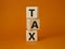 Tax symbol. Wooden cubes with word Tax. Beautiful orange background. Business and Finace and Tax concept. Copy space