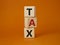 Tax symbol. Wooden cubes with word Tax. Beautiful orange background. Business and Finace and Tax concept. Copy space