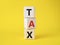 Tax symbol. Wooden cubes with word Tax. Beautiful yellow background. Business and Finace and Tax concept. Copy space