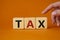 Tax symbol. Wooden cubes with word Tax. Businessman hand. Beautiful orange background. Business and Finace and Tax concept. Copy
