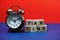 Tax Time alphabet letter with alarm clock on blue and red background