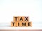 TAX TIME, text on wooden cube blocks stack isolated on wood table and white background, minimal style.