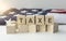 Taxe - text on wooden cubes, on wooden background. flower in a pot,