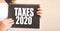 Taxes 2020 words on black notepad in businesswoman hands. business concept