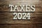 Taxes 2024 alphabet letter on wooden background