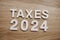 Taxes 2024 alphabet letters on wooden background