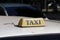 Taxi light sign or cab sign in drab brown color with black text on the car roof at the street blurred background