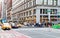 Taxis and people rush through the intersection of 23rd Street and 5th Avenue during a busy afternoon rush hour commute in Midtown