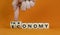 Taxonomy or economy symbol. Businessman turns cubes, changes the word economy to taxonomy. Beautiful orange table, orange