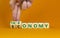 Taxonomy or economy symbol. Businessman turns cubes, changes the word economy to taxonomy. Beautiful orange table, orange