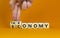 Taxonomy or economy symbol. Businessman turns cubes, changes the word economy to taxonomy. Beautiful orange table, orange