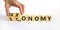 Taxonomy or economy symbol. Businessman turns cubes, changes the word economy to taxonomy. Beautiful white table, white background