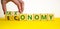 Taxonomy or economy symbol. Businessman turns cubes, changes the word economy to taxonomy. Beautiful yellow table, white