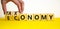Taxonomy or economy symbol. Businessman turns cubes, changes the word economy to taxonomy. Beautiful yellow table, white