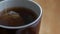 Tea bag floats in boiling water poured into a brown porcelain cup for breakfast