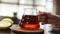 Tea being poured into glass transparent tea cup. Cup of tea. Sweets, hot tea and teapot. Ceramic teapot and glass teacup