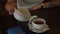 Tea being poured into glass transparent tea cup. Cup of tea. Sweets, hot tea and teapot. Ceramic teapot and glass teacup closeup.