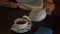 Tea being poured into glass transparent tea cup. Cup of tea. Sweets, hot tea and teapot. Ceramic teapot and glass teacup closeup.