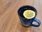 tea in a blue mug with a yellow lemon on a wooden surface