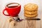 Tea in cup, stack of oat cookies with peanut, spoon, sugar on wooden table