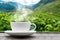 Tea cup on the wooden table and the blurred landscape tea plantations background