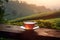 Tea cup with on the wooden table and the tea plantations background. Generative AI