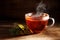 tea freshly brewed in a glass cup and some herbs on a dark rustic wooden background, healthy hot drink against cold and flu, copy