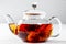 Tea in a glass teapot with a blooming large flower. Teapot with exotic green tea on white background