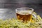 Tea of gray wormwood in glass cup on dark board