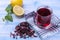 Tea karkade in a glass and leaves of hibiscus and lemon on a blue table