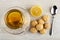 Tea with lemon in cup on saucer, piece of lemon, spoon, creamy fudge on wooden table. Top view