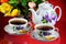 Tea party - tea in cups, teapot, garden flowers on a summer day. Daily tea is a delicious, popular, healthy, invigorating drink