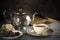 Tea in a porcelain cup, old fashioned silver teapot, chocolate c