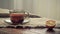 tea in a transparent glass cup and dried lemon on the edge of a rough burlap tablecloth on old boards in natural light