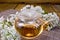 Tea with yarrow in glass teapot on bamboo
