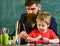 Teacher with beard, father and little son in classroom while drawing, creating, chalkboard on background. Talent and