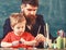 Teacher with beard, father and little son in classroom while drawing, creating, chalkboard on background. Talent and