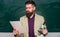 Teacher bearded man hold documents and microscope chalkboard background. Explaining theory. College and high school