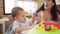 Teacher with boys playing with construction blocks sitting on table at kindergarten